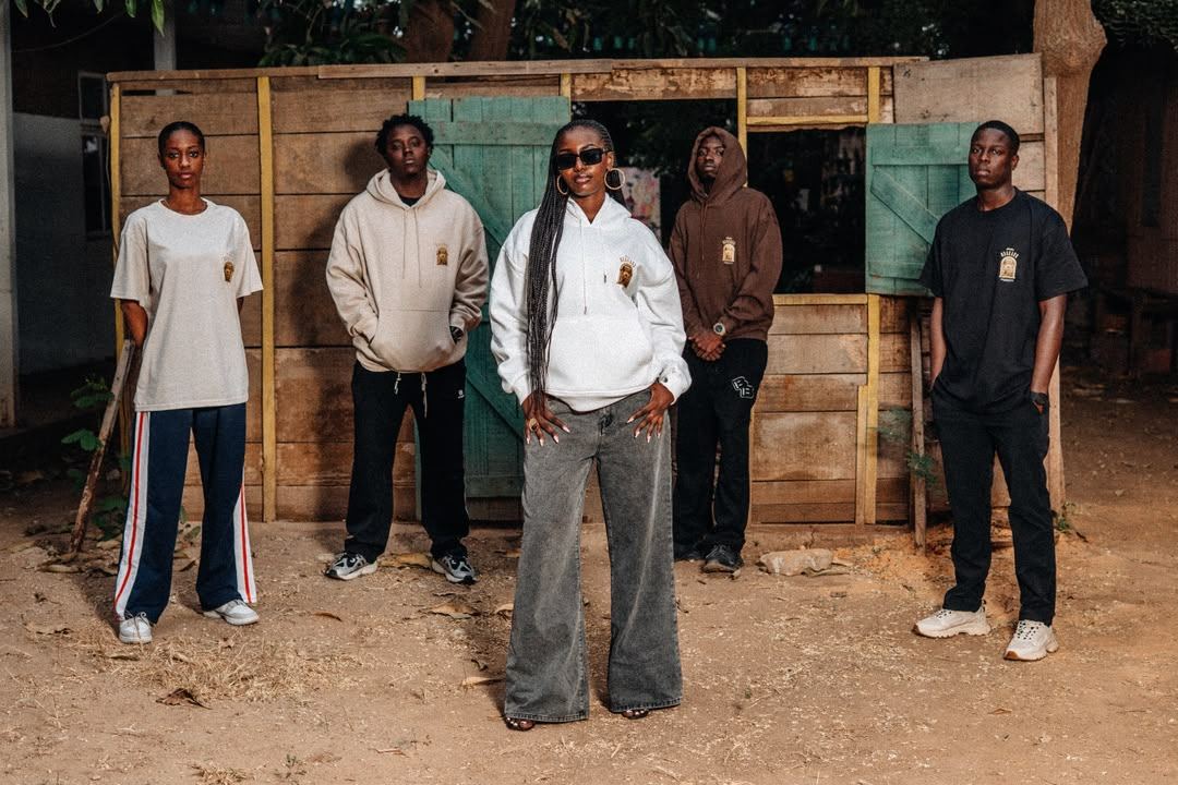 Cinq modèles en t-shirts et hoodies Mbedüm Ndakaru devant une devanture en bois à Dakar