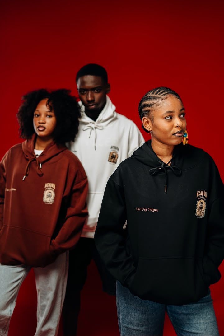 Trois hoodies Mbedüm Ndakaru bordeaux, blanc et noir sur fond rouge